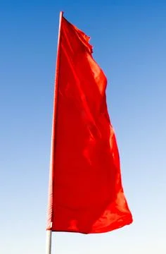Red flag of rectangular shape elongated fluttering in the wind on the flagpol 写真素材