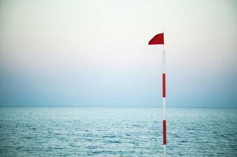 Red flag warning danger at tranquil sea horizon Stock Photos