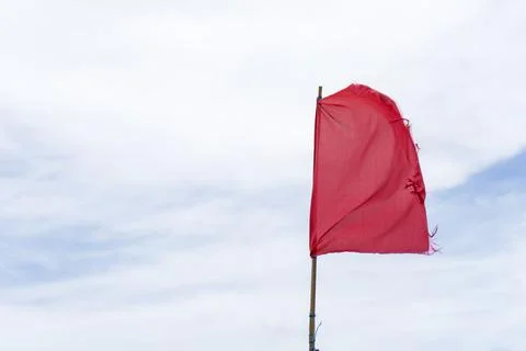 Red flag warning flags danger wind blue sky background Stock Photos