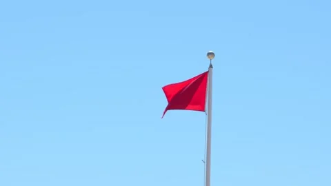 Red Flag Warning Slow Motion Waving Against Blue Sky. Signaling Hazardous S.. Stock Footage 336922150