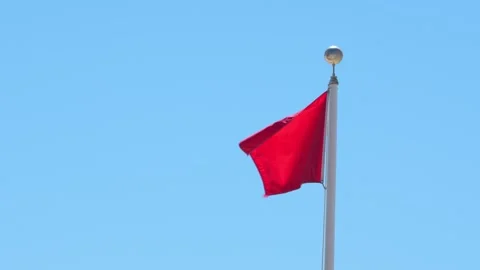 Red Flag Warning Slow Motion Waving Against Blue Sky. Signaling Hazardous S.. Stock Footage 336922211