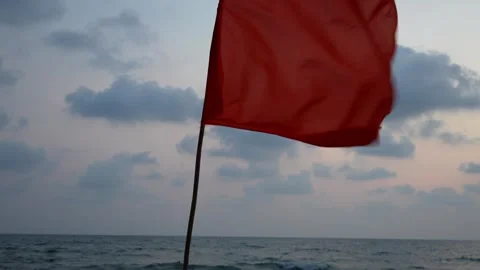 Red flag waving on the beach at sunset Video stock 306737759