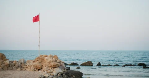 Red flag waving at seashore against clear blue sky Stock Footage 249764962