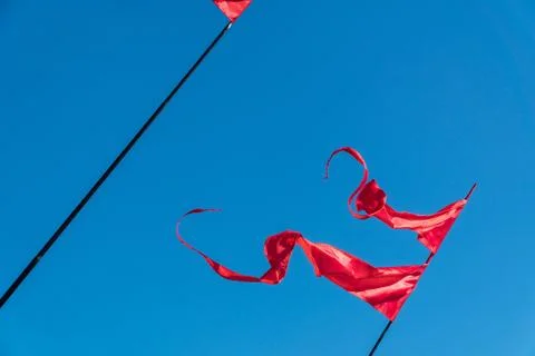 Red flags are fluttering in the wind against the blue sky Stock Photos