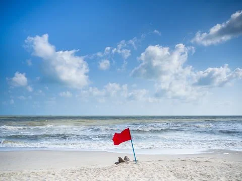 Red flags are placed on the sand at the beach to warn against swimming. warni Stock Photos