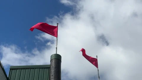 Red flags flying in the wind against a blue sky with moving clouds Stock Footage 332722463