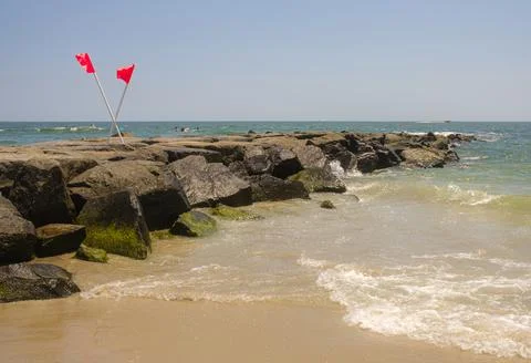 Red Flags on Ocean Rock Jetty, Safety Amidst the Waves Stock Photos