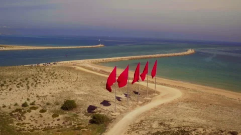 Red Flags Wave on Morocco Coastal Spit Aerial Stock Footage 336571927