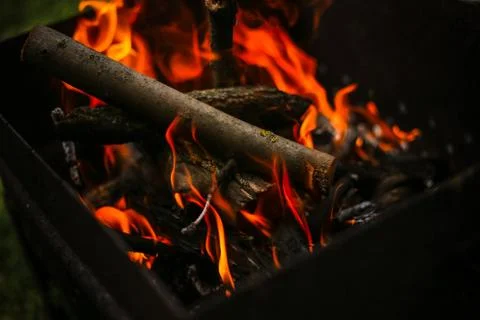 Red flame from a cut of a tree, dark gray coals inside a metal brazier. Firew Foto stock