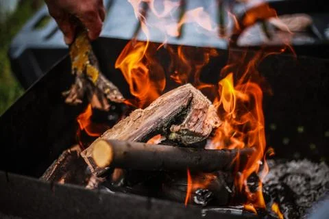 Red flame from a cut of a tree, dark gray coals inside a metal brazier. Firew Stock-Fotos
