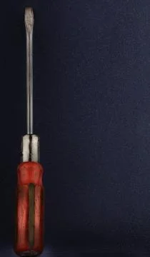 Red flathead screwdriver on a blue background, tool Stock Photos
