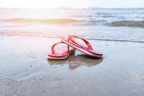Red flip flops on beach with sandy beach sea ocean and sunlight background Foto stock