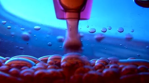 Red Fluid / Oil droplets / bubbles collecting in water filled container Video stock 42987618