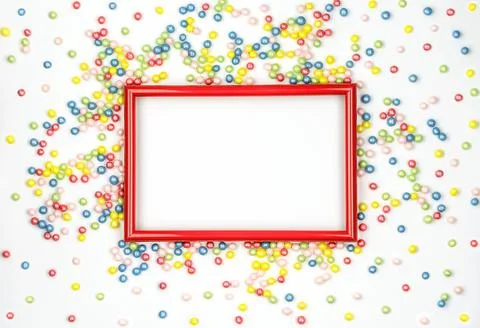Red frame and multicolored candy on white background. Festive mock up Фото