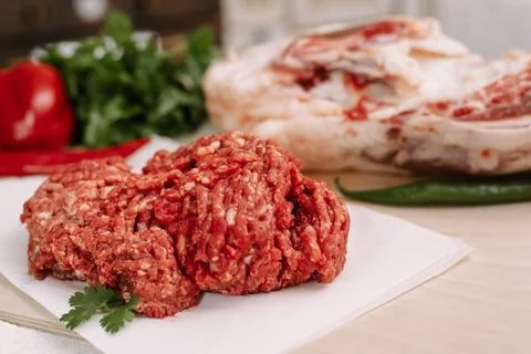 Red fresh minced meat on the background of lamb legs, red pepper and greens.. Stock Photos