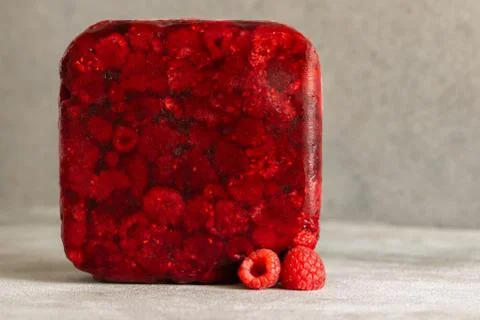 Red frozen raspberry cube. Creative photo. Copy space. Stock Photos