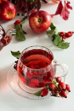 Red fruit tea infusion with apples and rosehips on a white table Stock Photos