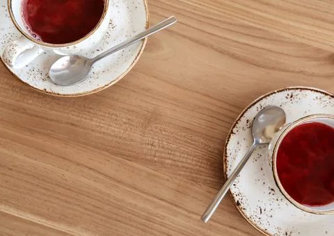 Red fruit tea in trendy ceramic white cups with brown decor on wooden table.  Stock Photos