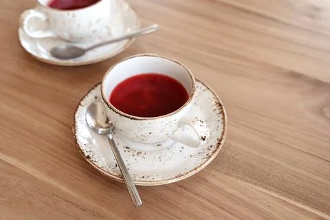 Red fruit tea in trendy ceramic white cups with brown decor on wooden table.  Stock Photos
