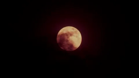 Red full moon behind shadow of cloud in dark sky night time. Stock Photos