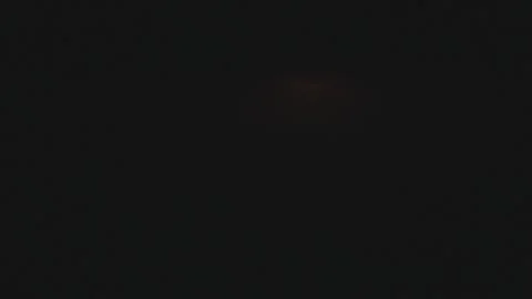 Red full moon disappearing below the horizon line in a dark night sky 스톡 동영상 344307827