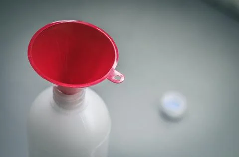 Red funnel in a plastic bottle. Selective focus, copy space Stock Photos