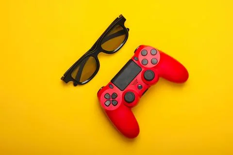 Red game controller and sunglasses on yellow background Stock Photos
