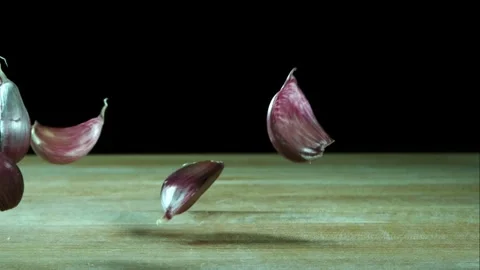 Red garlic cloves falling and bouncing on wood 動画素材 327632276