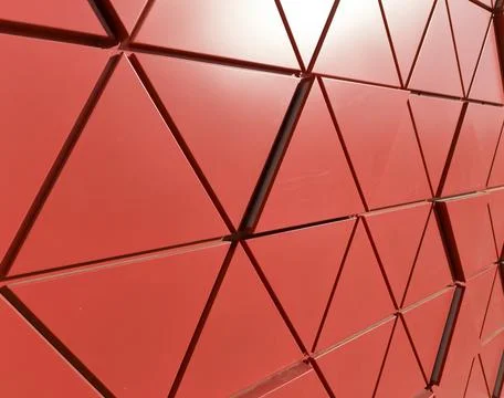Red geometric facade with triangular panels forming dynamic architectural Фото