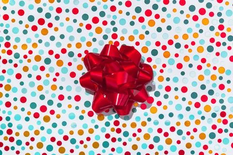 Red gift bow on multicolor wrapping paper Stock Photos