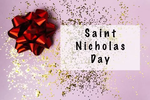 Red gift bow on a pink background with golden glitter, celebrating festive Stock Photos