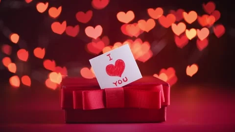 Red gift box, accompanied by a card featuring a red heart and text i love you Stock Footage 301296126