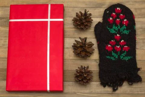 Red gift box and pine cone with mitten Stock Photos