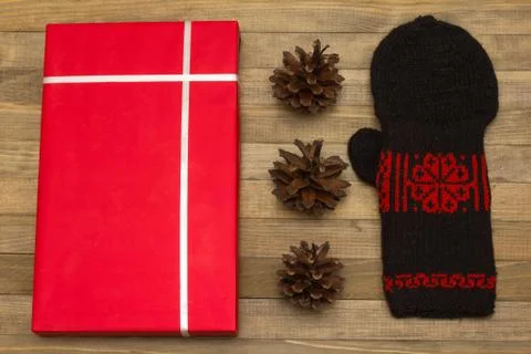 Red gift box and pine cone with mitten Stock Photos