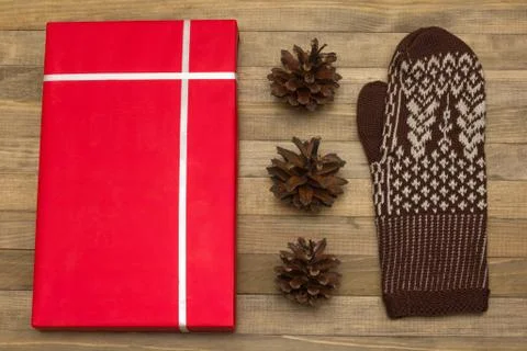 Red gift box and pine cone with mitten Stock Photos