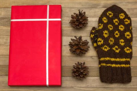 Red gift box and pine cone with mitten Stock Photos