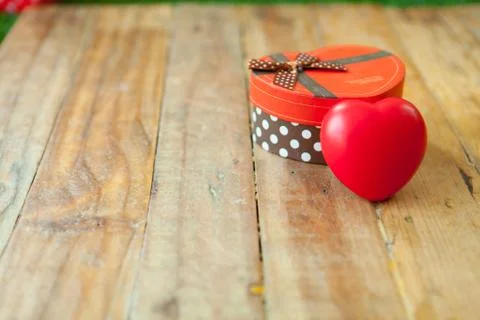 Red gift box and red ribbon and mini heart inside on wood background with spa Foto stock