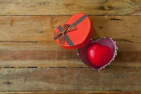 Red gift box and red ribbon and mini heart inside on wood background with spa Stock Photos