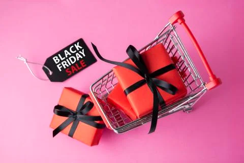 Red gift box with black bow in shopping cart with black friday sale tag on pi Stock Photos