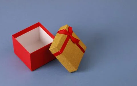 Red gift box with bow and yellow lid on blue background. Stock Photos