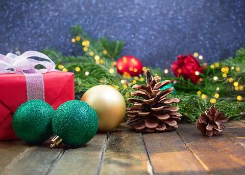 Red gift box with bow, glitter balls, pinecones on wooden background Stock Photos