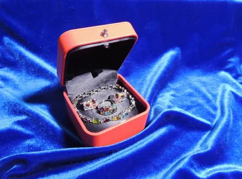 Red gift box with a bracelet, ring and earrings inside Stock Photos