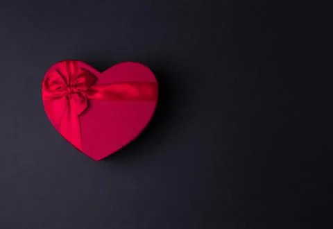 Red gift box heart shape with red ribbon on a black background, gift concept  Stock Photos