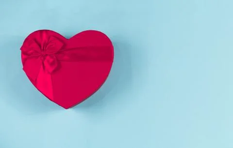 Red gift box heart shape with red ribbon on a blue background, gift concept V Stock Photos