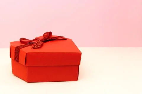 Red gift box in a heart shape with glittering ribbon bow Foto stock