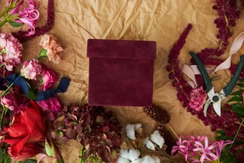 The red gift box with a place for text is framed by flowers and things of the Stock Photos