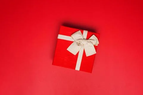 Red gift box on red background. Gift box tied with gold ribbon and bows on re Stock Photos