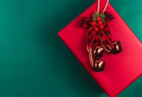 Red gift box with red bow and bells on green background Stock Photos