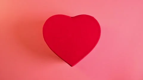 Red gift box shape of heart and flying red confetti hearts on pink background Stock Footage 169598657