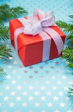 Red gift box with shiny silver bow on blue background with stars Stock Photos